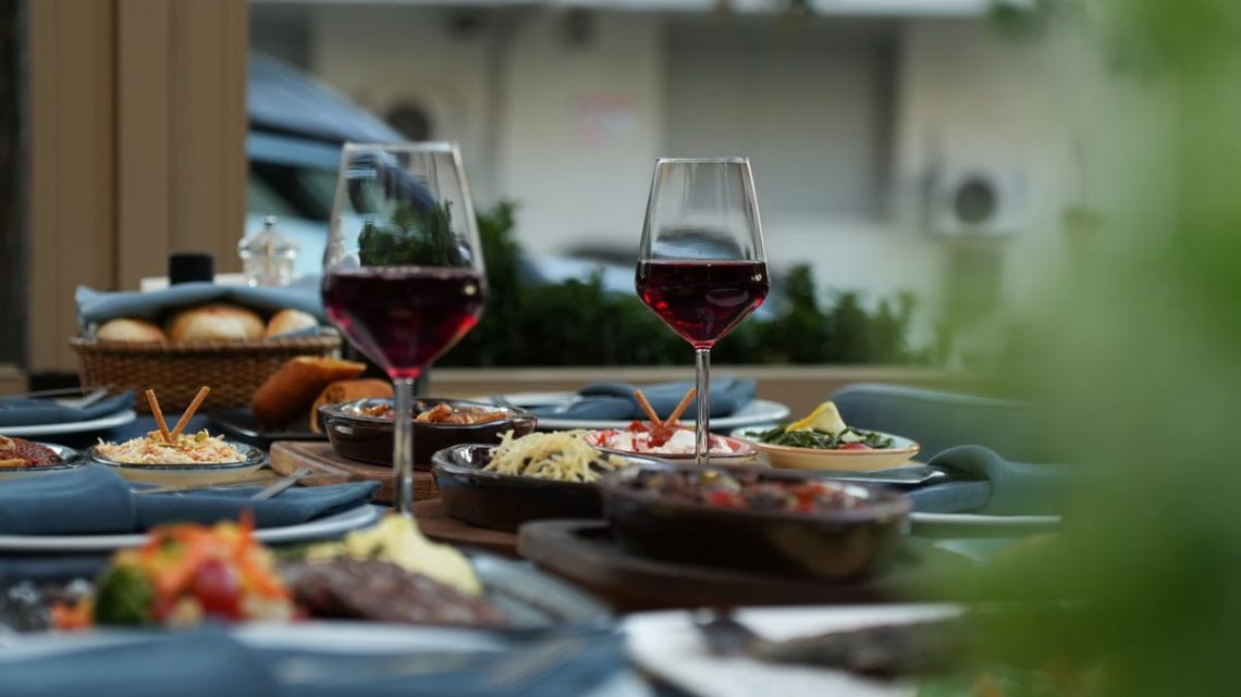 Luxurious outdoor table setting featuring red wine and a variety of gourmet dishes for a sophisticated dining experience.