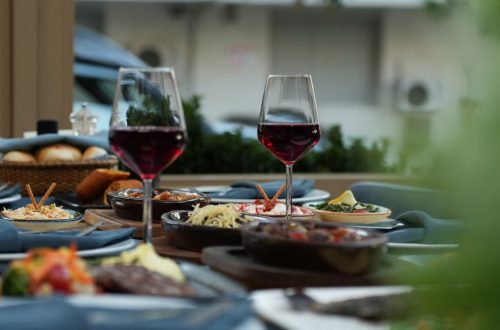 Luxurious outdoor table setting featuring red wine and a variety of gourmet dishes for a sophisticated dining experience.