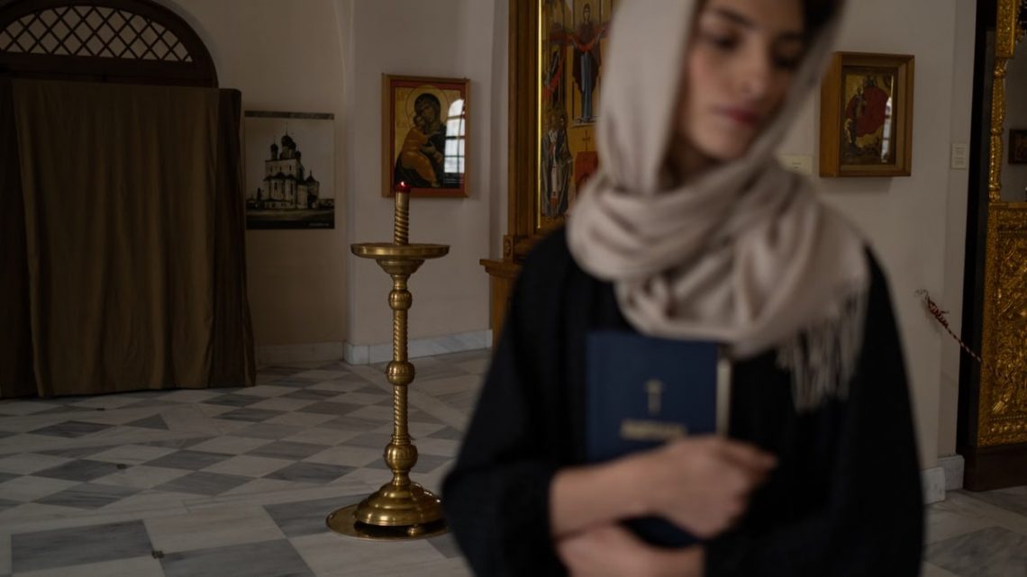 Woman with headscarf holding book in serene church setting, embodying spirituality.