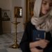 Woman with headscarf holding book in serene church setting, embodying spirituality.
